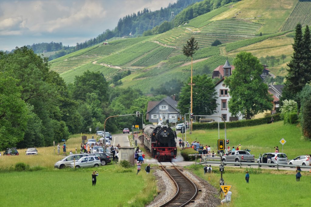 Achertalbahn überquert einen Bahnübergang und wird von vielen begeisteten Menschen bestaunt. 