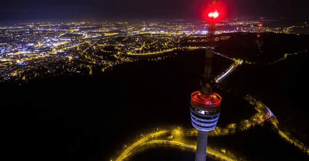 Der Stuttgarter Fernsehturm und Antenne bei Nacht, im Hintergrund die Stuttgarter Innenstadt
