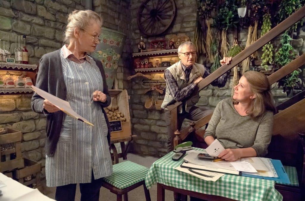 Evelyn Riedle (Catharina Kottmeier, re.) macht für Johanna (Ursula Cantieni, li.) die Steuer, dafür verrät Johanna ihr das Geheimnis um die perfekte Schwarzwälder Kirschtorte. Im Hintergrund Karl (Peter Schell, Mi.)
