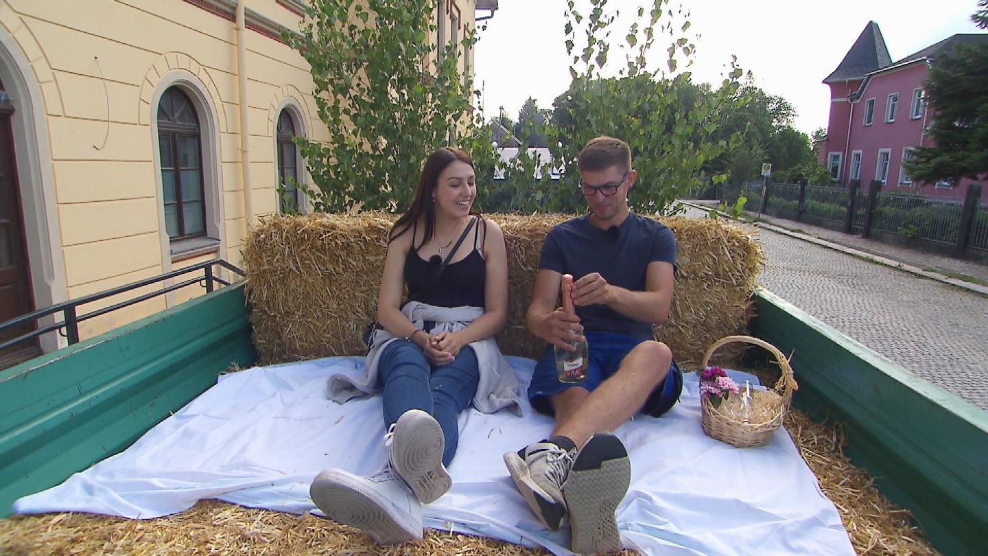 Mutterkuhhalter Paul (22) aus Sachsen holt Sarah (20, Kindergärtnerin) mit einem Anhänger voll Stroh zur Hofwoche am Bahnhof ab.