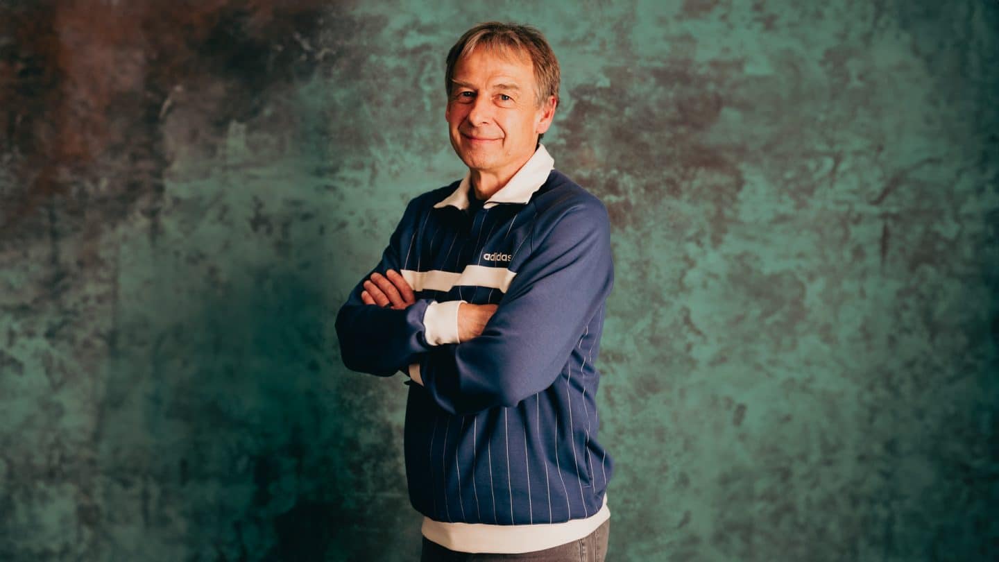 Jürgen Klinsmann lächelt mit verschränkten Armen in die Kamera.
