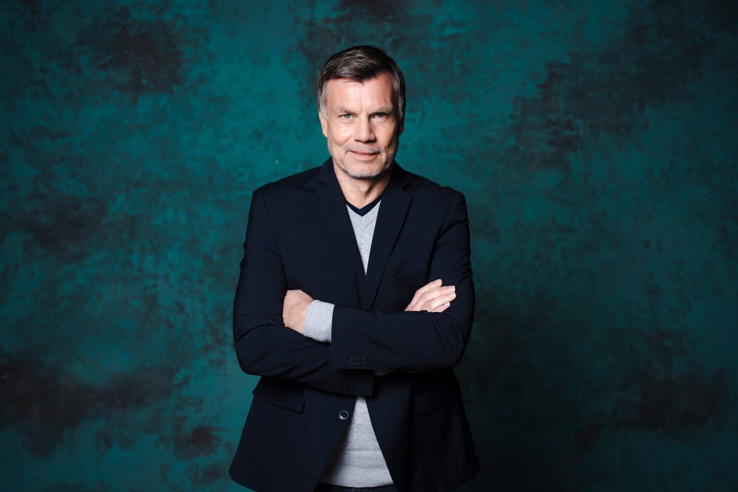 Thomas Helmer mit verschränkten Armen lächelt in die Kamera.