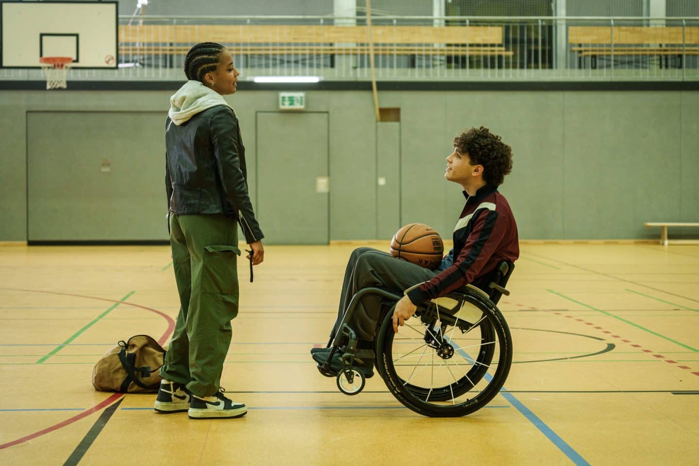 "Hameln - Verloren": In einer Sporthalle stehen sich Romy Jost (Pia Amofa-Antwi) und Ruben Zastrow (Riccardo Campione) gegenüber. Ruben, der im Rollstuhl sitzt, hat einen Basketball auf dem Schoß.

