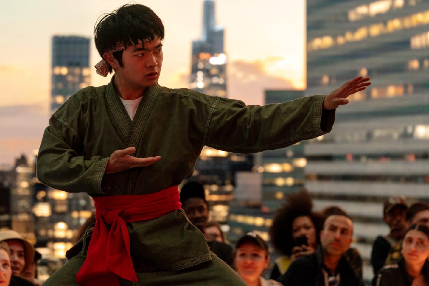 Ben Wang als Li Fong in ‚Karate Kid: Legends‘ – beeindruckende Kampfpose im Sonnenuntergang vor der Skyline einer Großstadt.