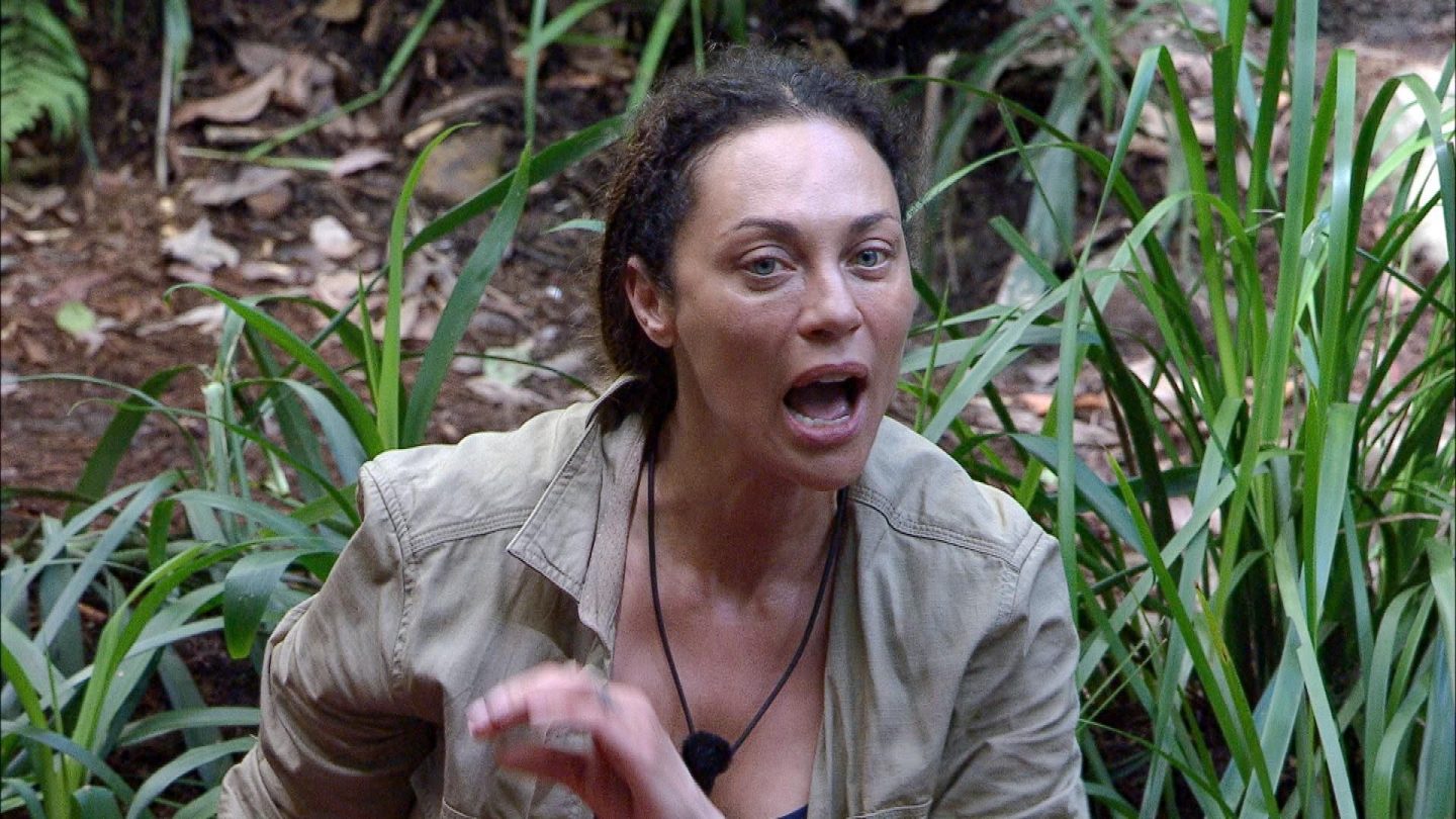 Lilly Becker sitzt im Dschungelcamp zwischen grünen Pflanzen und gestikuliert heftig, während sie sichtlich aufgebracht spricht. Ihr Gesichtsausdruck zeigt Wut und Frustration. Sie trägt eine beige Jacke und eine schwarze Kordel mit Mikrofon um den Hals. Die Szene spielt sich am Lagerfeuer ab, wo Maurice sie gerade zur Versöhnung mit Sam aufgefordert hat – doch Lilly lehnt entschieden ab und macht ihrem Ärger Luft.