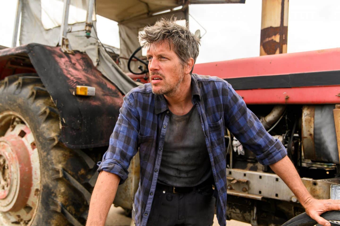 "Friesland – Landfluchten": Dirk Poppinga (Nic Romm) steht vor einem Traktor und blickt angespannt in die Ferne.