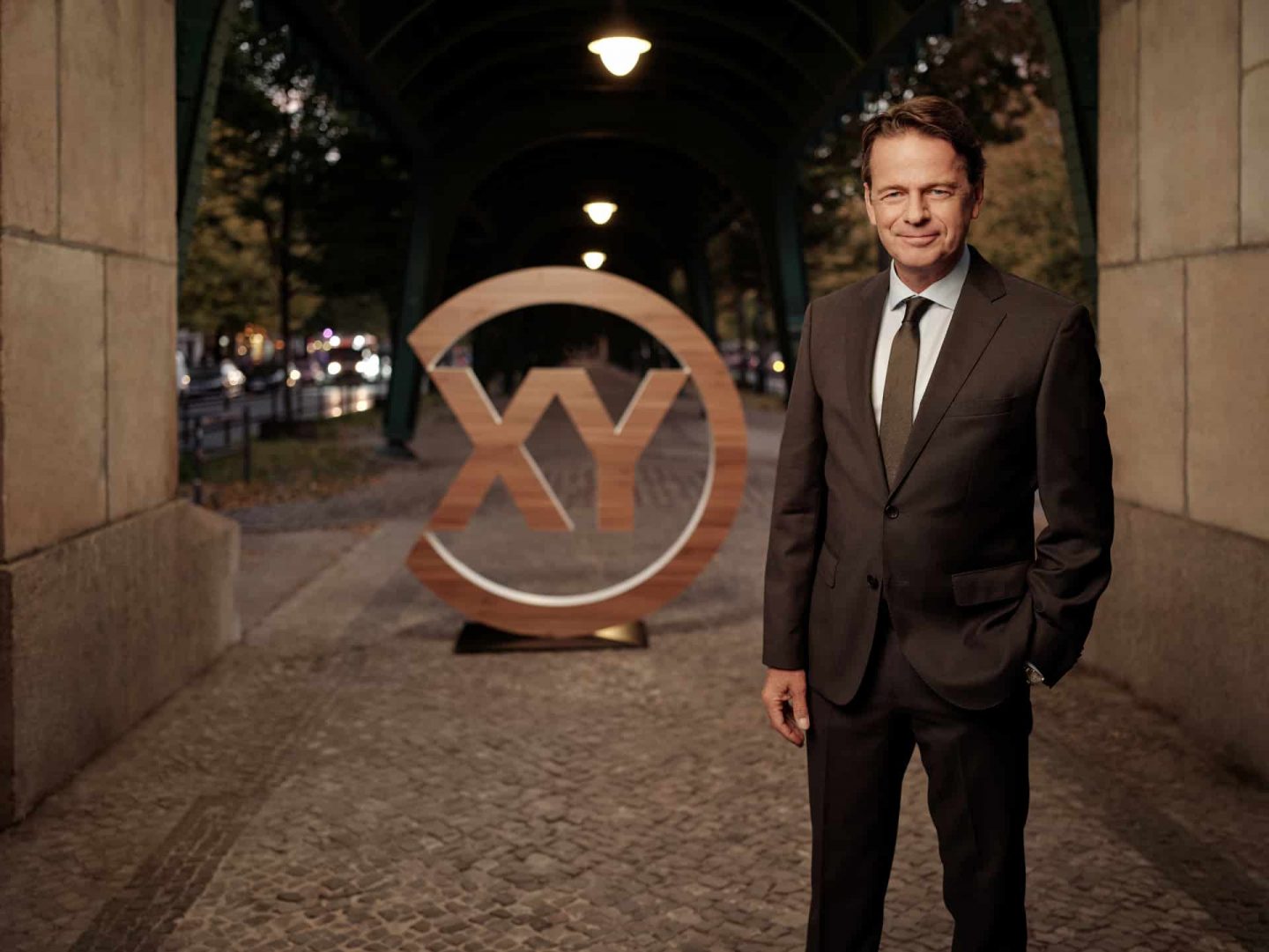 "Aktenzeichen XY… Ungelöst": Rudi Cerne steht vor dem "XY"-Logo und lächelt in die Kamera.
