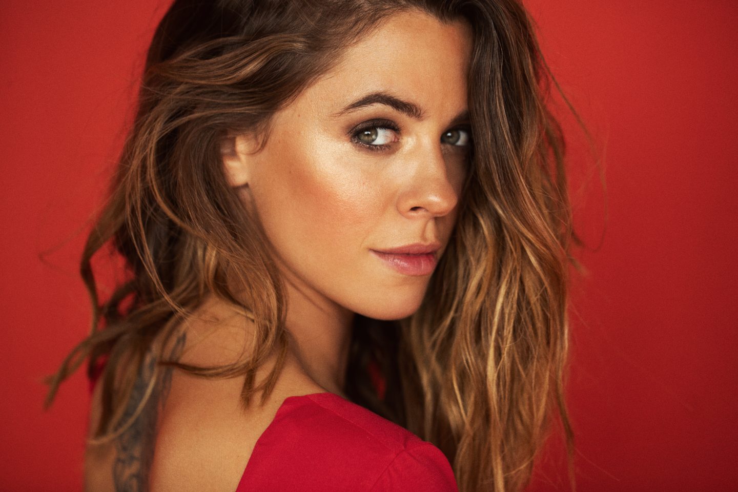 Vanessa Mai, deutsche Schlagersängerin, in einem roten Outfit vor einem roten Hintergrund.