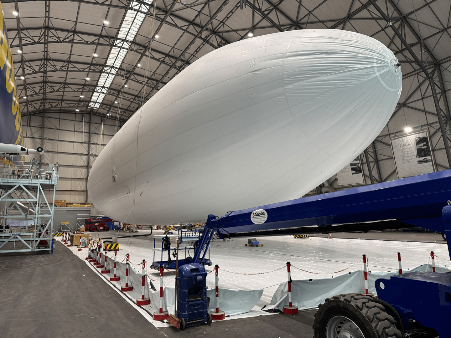 Der Europa-Park Zeppelin in einer großen Halle während der Vorbereitungsarbeiten für seinen Einsatz in der Jubiläumssaison 2025, umgeben von Absperrungen und technischen Geräten.








