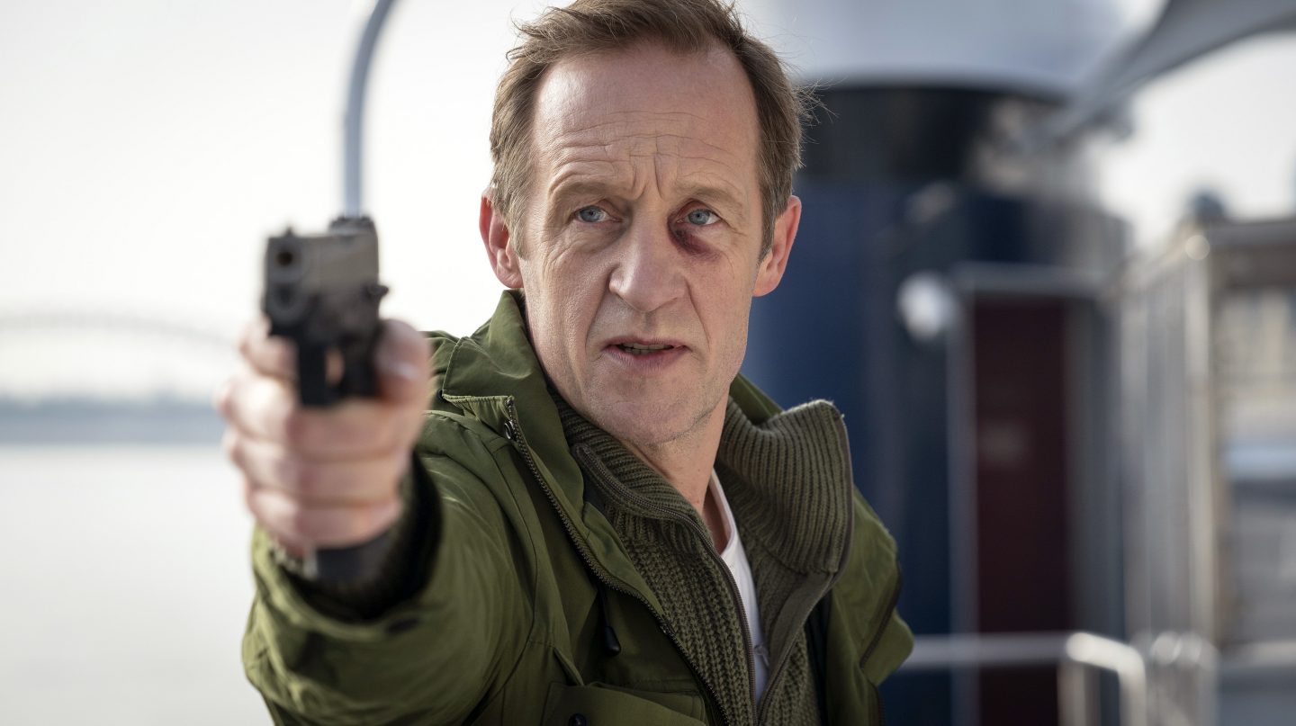 Entführer Daniel Huberty (Stephan Kampwirth) richtet an Deck des entführten Rheinschiffes eine Waffe auf Kommissar Max Ballauf.
