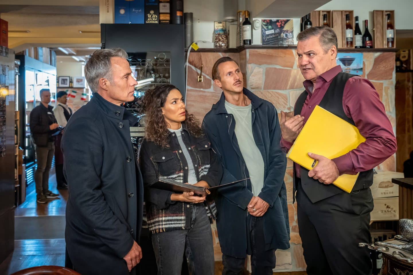 "SOKO Leipzig - Italien kann sehr kalt sein": Jan Maybach (Marco Girnth), Kim Nowak (Amy Mußul) und Moritz Brenner (Johannes Hendrik Langer) befragen Amando Popp (Tom Quaas) im Gastraum seines Restaurants. Die Stimmung ist angespannt.
