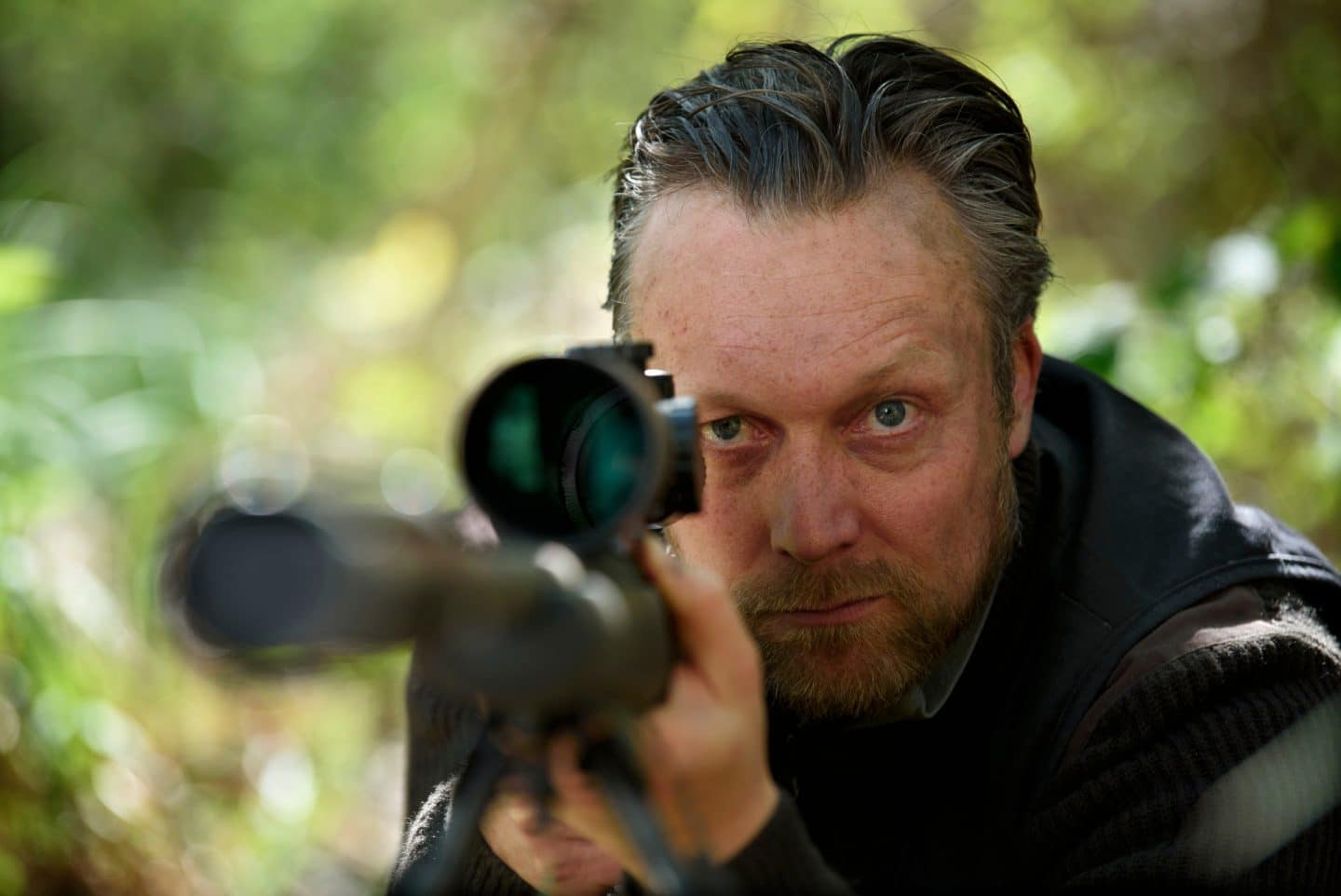 "Spreewaldkrimi - Böses muss mit Bösem enden": Im Grünen: Felix Hoffmann (Robin Sondermann) blickt durch sein Gewehr in Richtung Kamera.
