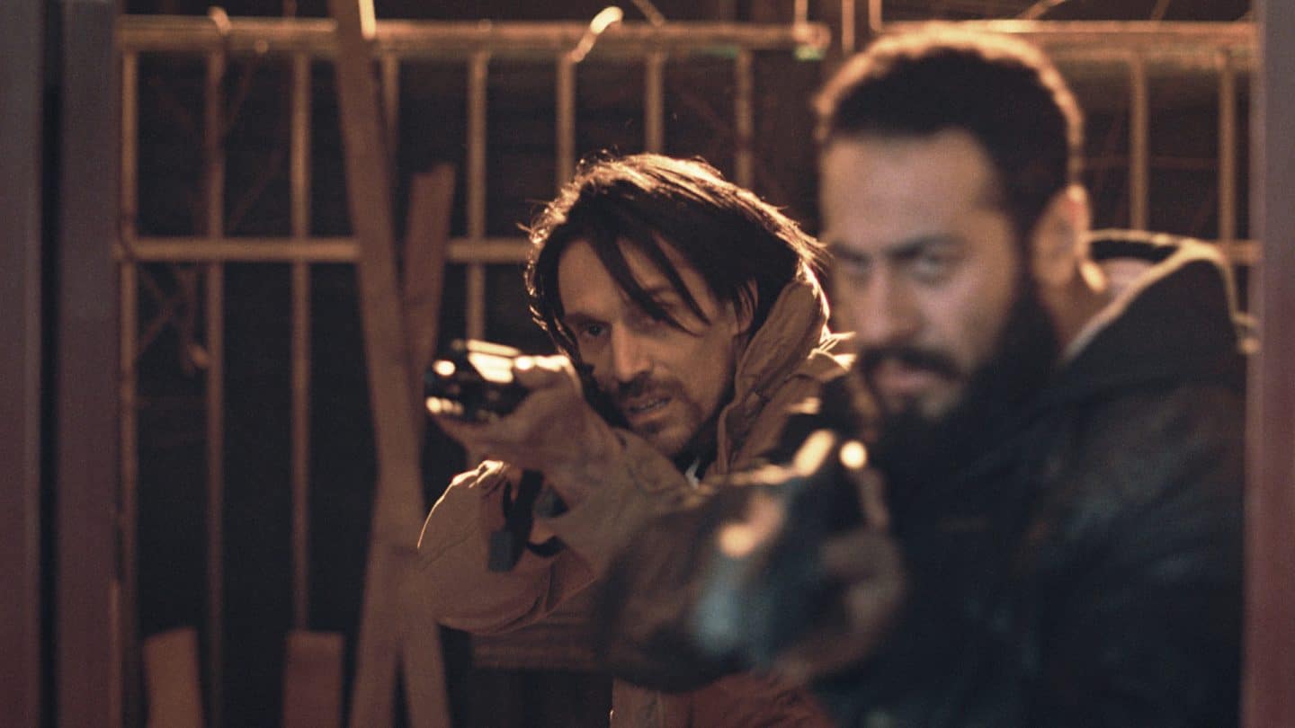 "Jericho Ridge - Unter Beschuss": Die Angreifer Carter (Philipp Christopher, l.) und Kreshnik (Trim Ademi, r.) stehen nebeneinander und zielen mit jeweils einem Gewehr seitlich nach vorne.
