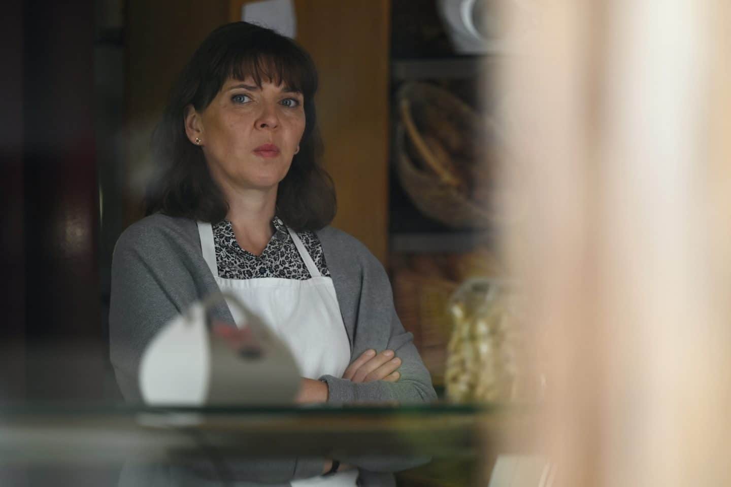 "Frühling - Die Mutter, die es nie gab": Heidrun Niedermayer (Catalina Navarro Kirner) schaut mit ernstem Blick aus dem Schaufenster ihrer Bäckerei nach draußen.
