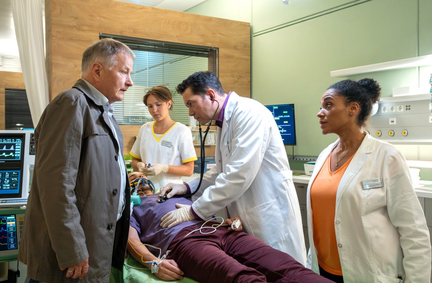 Jonas Heilmann (Anthony Petrifke, liegend) ist zu Hause bewusstlos zusammengebrochen. Dr. Philipp Brentano (Thomas Koch, 2.v.re.) hat den Verdacht, dass es eine Blutung im Hirn sein könnte. Dr. Roland Heilmann (Thomas Rühmann, li.) will natürlich bei seinem Enkel bleiben. Doch die Leiterin der Notaufnahme Dr. Lucia Böhm (Vanessa Rottenburg, re.) macht ihm unmissverständlich klar, dass er in diesem Fall "nur" Angehöriger ist. Roland ist nun zum Warten verdammt.
