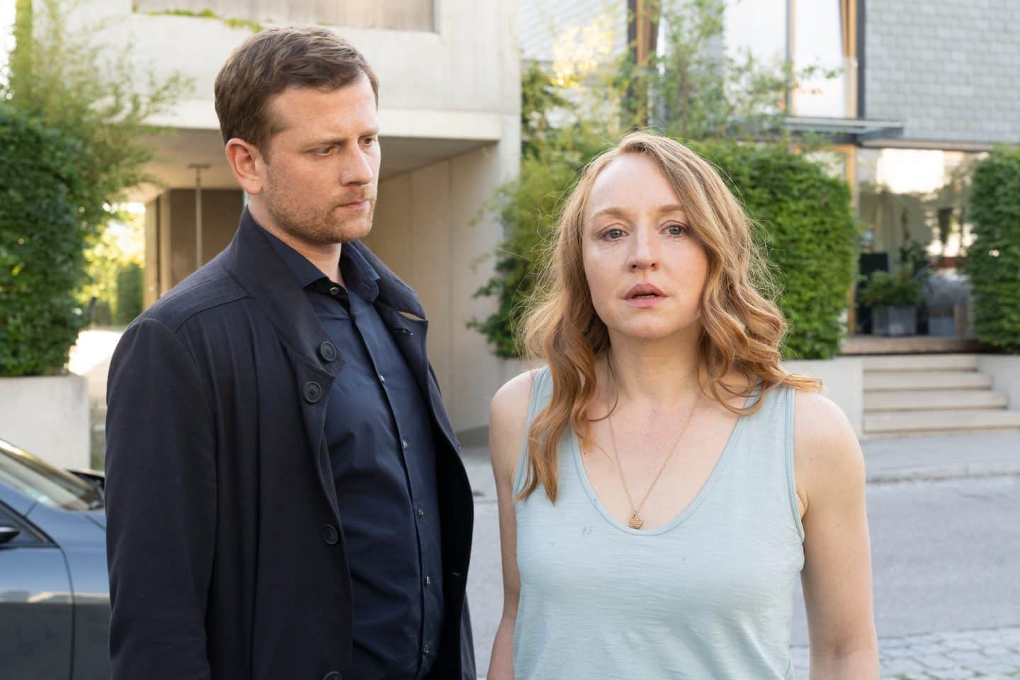 "Die Chefin - Murnau": Maximilian Murnau (Christoph Schechinger) steht besorgt vor einem Wohnhaus und betrachtet die neben ihm stehende, verängstigte Monika Lührs (Brigitte Hobmeier).
