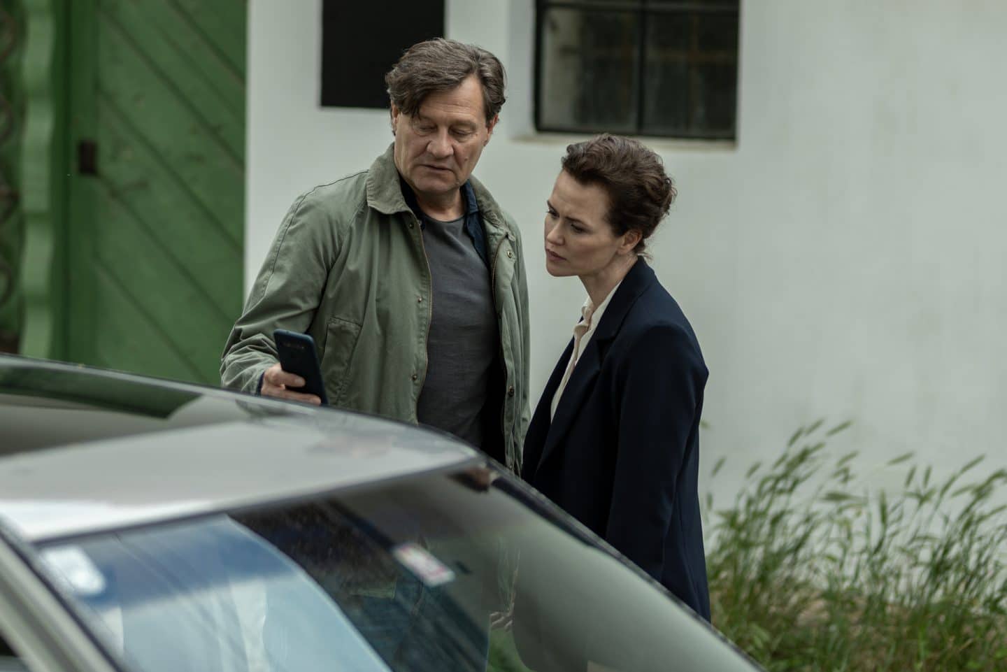 "Wiener Blut - Berggericht": Fida Emam (Melika Foroutan) und Markus Glösl (Harald Windisch) stehen zusammen an einem Auto. Markus Glösl zeigt Fida Emam etwas auf seinem Handy.