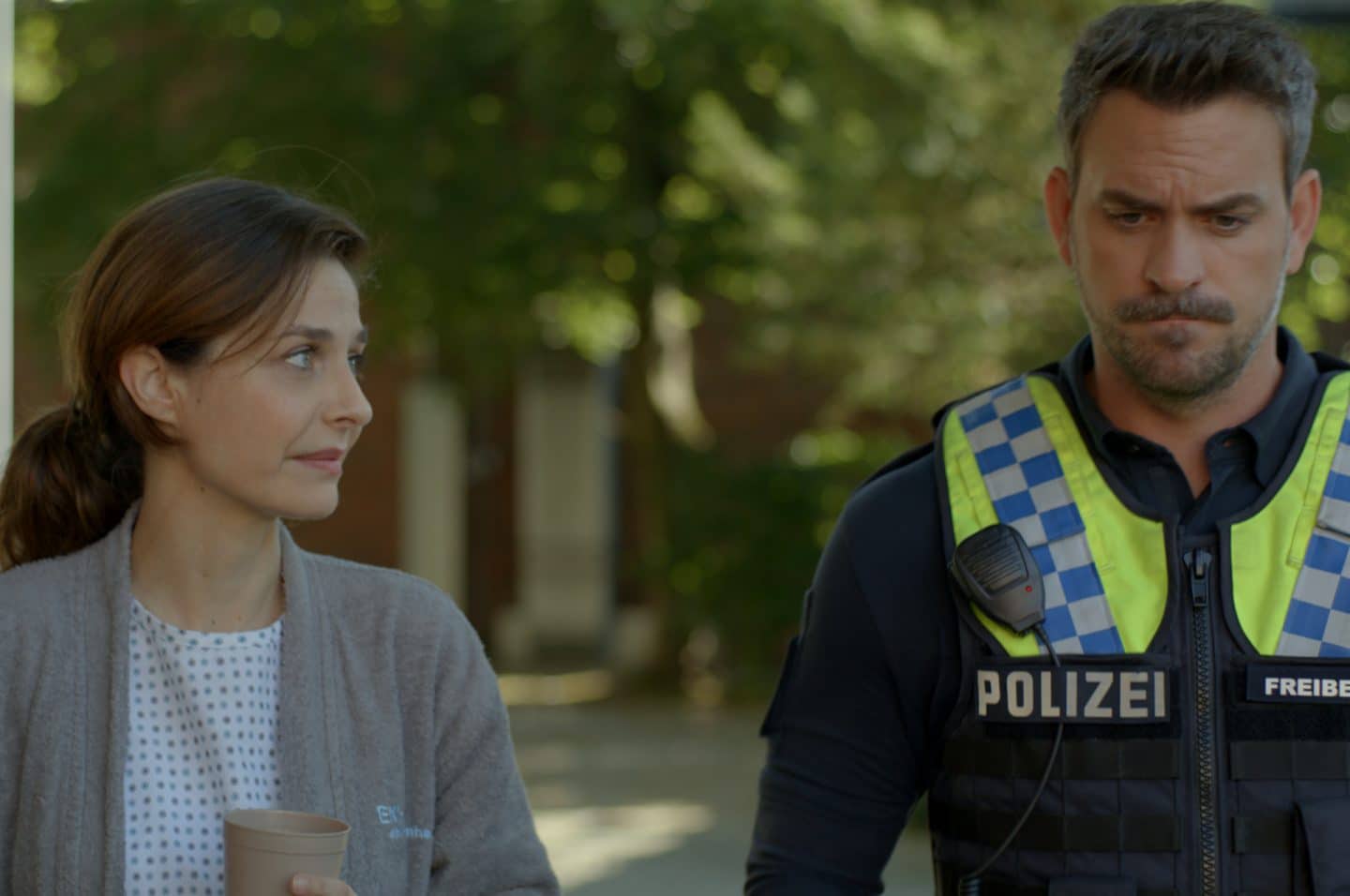 "Notruf Hafenkante - Der Preis der Lüge": Nina Hoffmann (Anne Werner) und der Polizist Kris Freiberg (Marc Barthel) gehen nebeneinander einen Weg entlang. Kris blickt nachdenklich ins Leere. Nina schaut ihn von der Seite an.