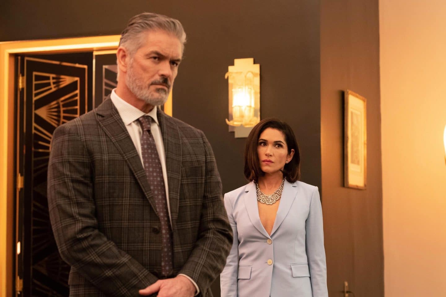 "The Man From Toronto": Colonel Marin (Alejandro De Hoyos) und Daniela Marin (Lela Loren) stehen mit ernsten Gesichtern in einem Zimmer.
