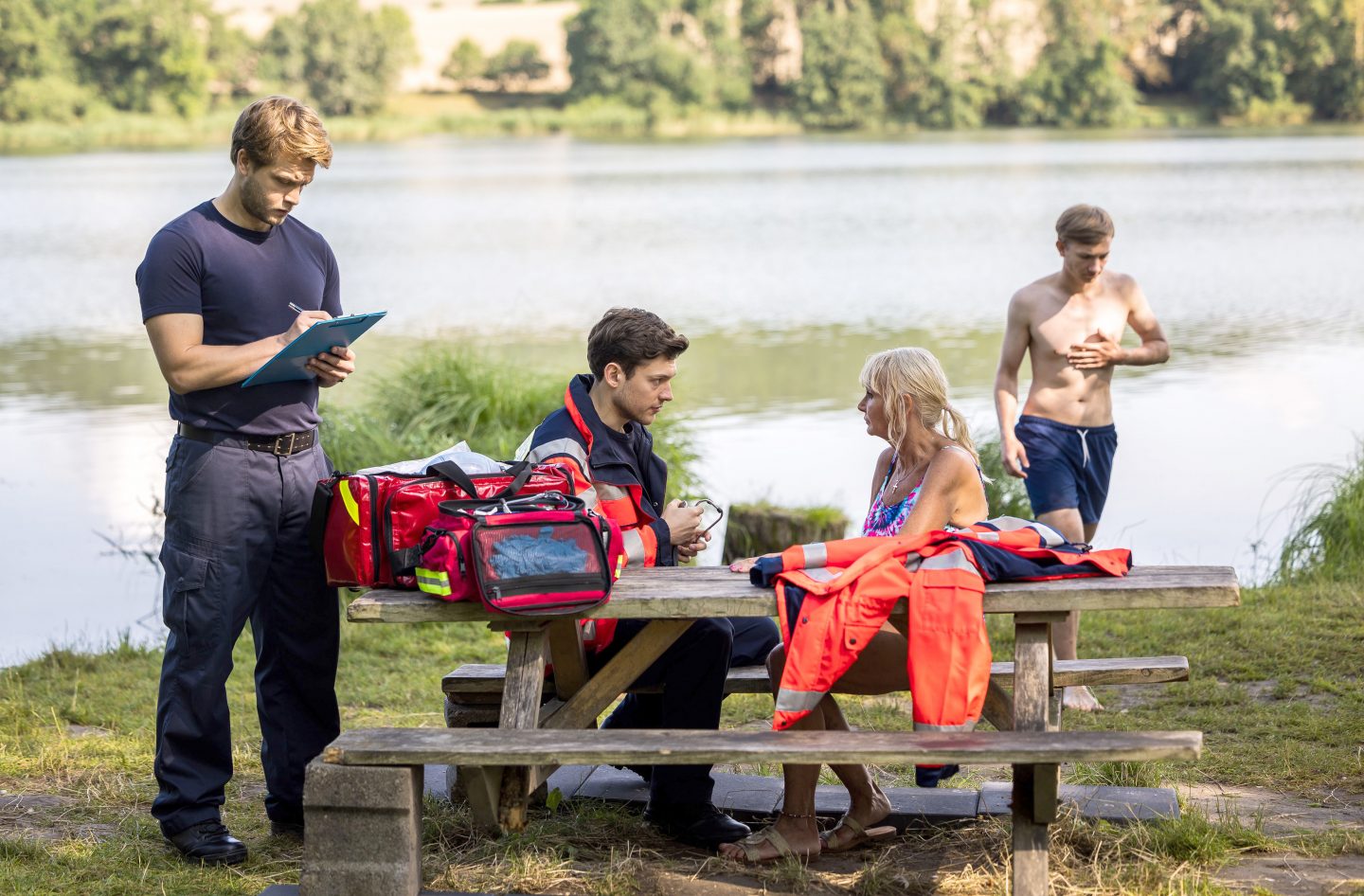 Dr. Mikko Rantala (Luan Gummich, l.) und Florian Osterwald (Lion Wasczyk, 2.v.l.) helfen einer Notfallpatientin am See (mit Kompase, h.).