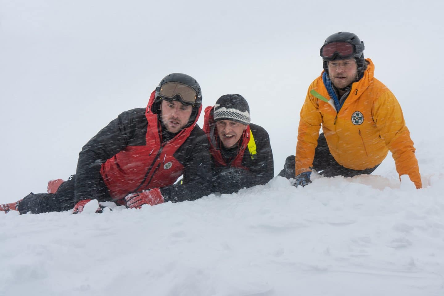 "Die Bergretter: Eiskalte Wahrheit (2)": Simon (Ferdinand Seebacher), Rudi (Michael Pascher) und Markus (Sebastian Ströbel) liegen in voller Montur im Schnee, ihre Blicke sind bestürzt. Es schneit.
