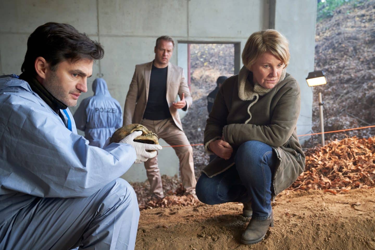 "Marie Brand und der Tote im Trikot": Marie Brand (Mariele Millowitsch) kniet zusammen mit dem Forensiker Konstatin Stark (Lenn Kudrjawizki) vor dem Fundort des Skeletts. Dahinter steht Jürgen Simmel (Hinnerk Schönemann).

