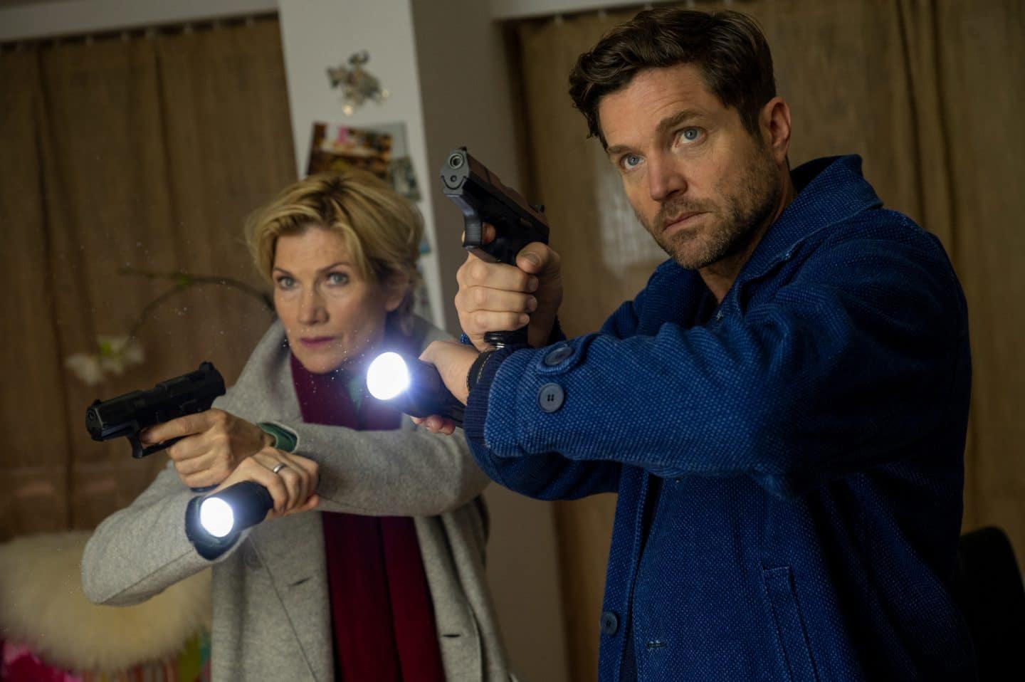 "SOKO Stuttgart – Letztes Kapitel": Kriminalhauptkommissarin Martina Seiffert (Astrid M. Fünderich) und Kriminalhauptkommissar Jo Stoll (Peter Ketnath) stehen mit gezogenen Dienstwaffen in einem Wohnraum. In der anderen Hand halten sie Taschenlampen. Die Stimmung wirkt angespannt, Stolls Blick ist leicht nach oben gerichtet.