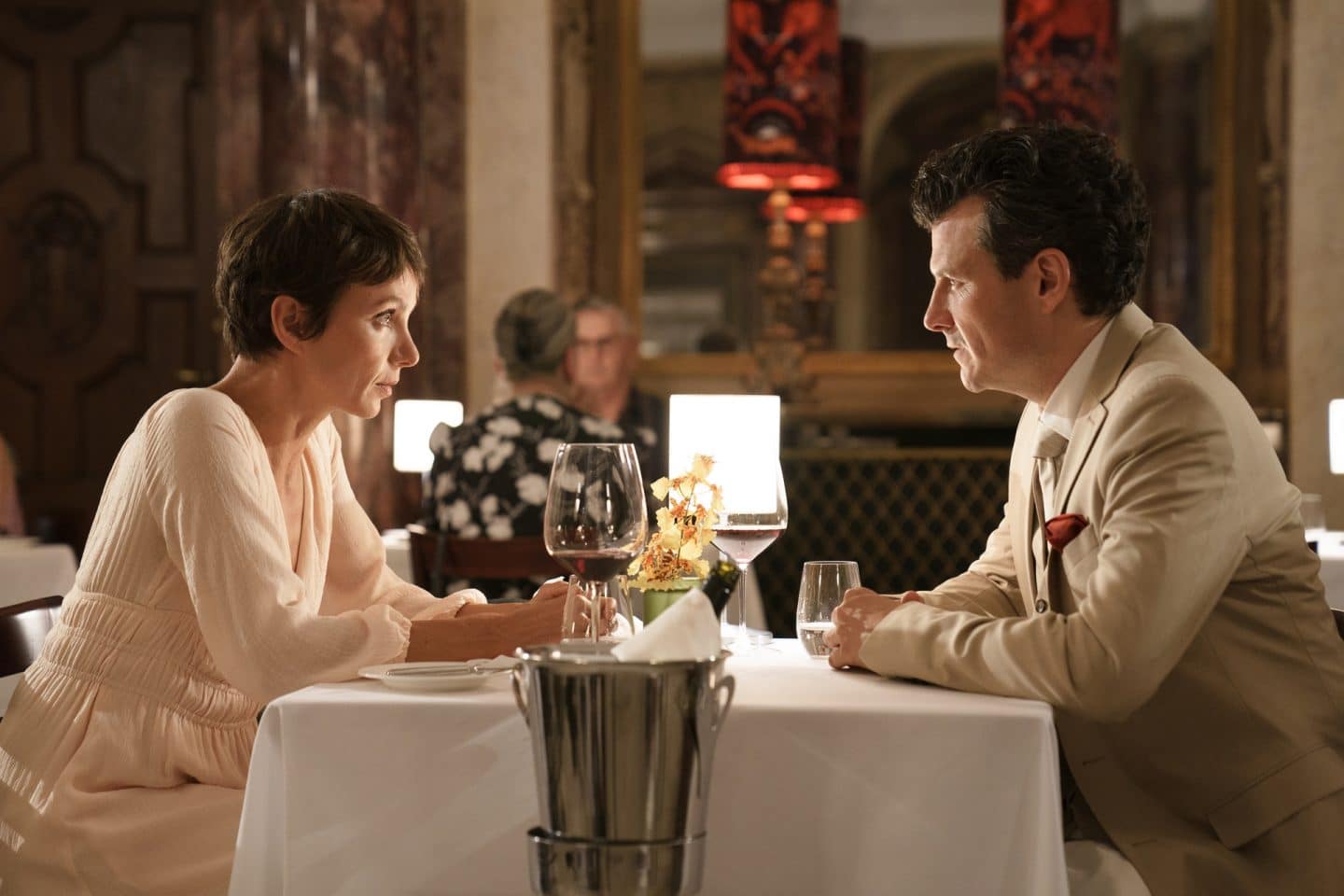 "Ewig Dein": Judith (Julia Koschitz) und Hannes (Manuel Rubey) sitzen sich im Restaurant an einem festlich gedeckten Tisch gegenüber und blicken sich kritisch in die Augen. Vor dem Tisch steht ein Weinkühler. Im Hintergrund des vornehmen Restaurants, das mit Marmorsäulen und großen Spiegel ausgestattet ist, sitzen andere Gäste (Komparsen).