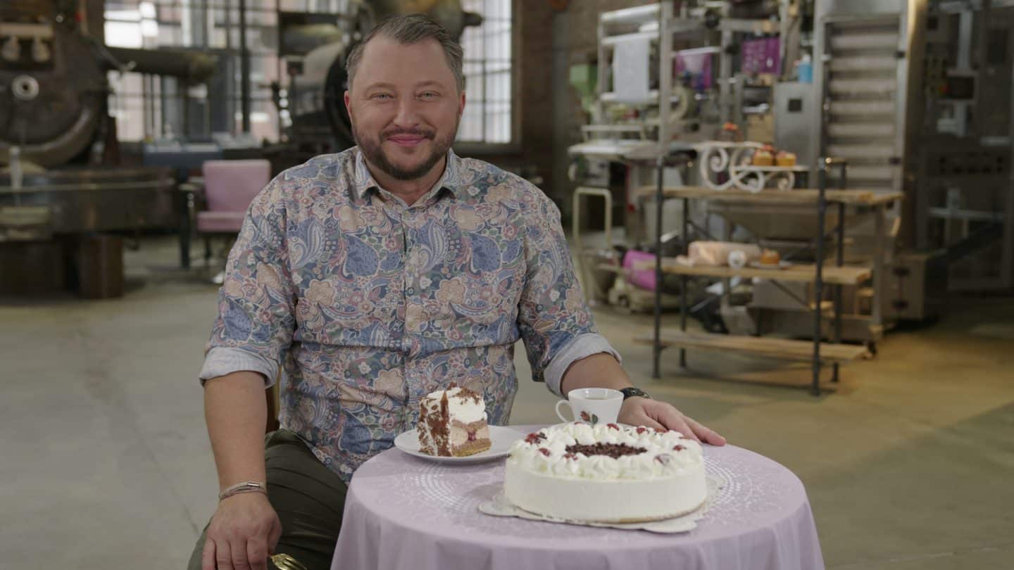 "besseresser: Die Tricks von Ferrero, Backwerk & Co.": Sebastian Lege sitzt an einem Tisch, auf dem eine Schwarzwälder Kirschtorte steht.