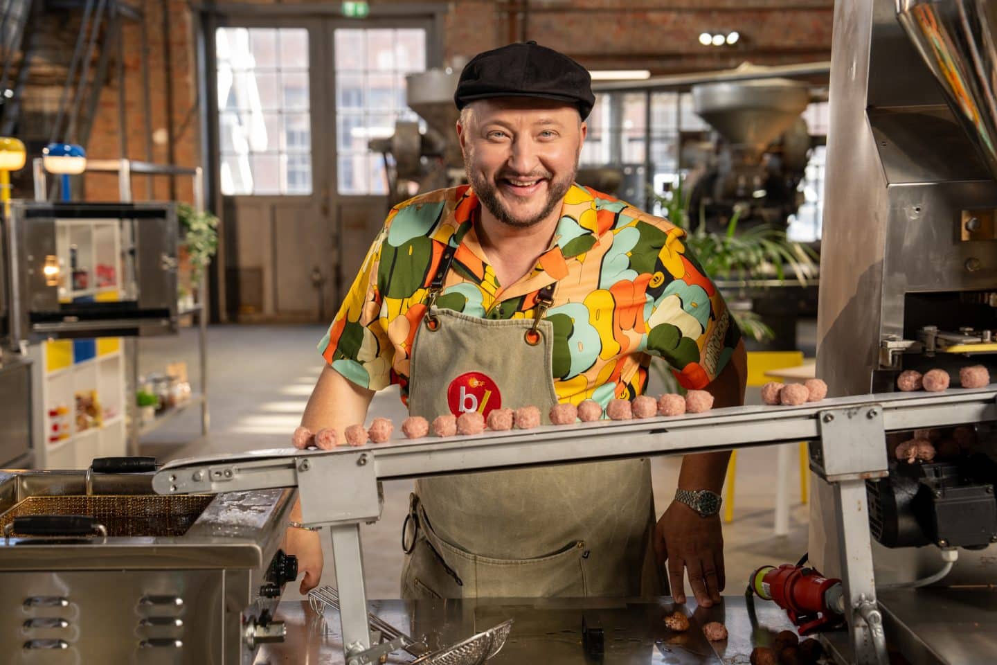 "besseresser: Die Tricks von Ikea - Kötbullar, Hot Dog & Co. - Sebastian Lege deckt auf": Sebastian Lege steht in seiner Werkstatt. Vor ihm ist ein Laufband das zu einer Friteuse führt. Darauf liegen Kötbullar, schwedische Hackbällchen.