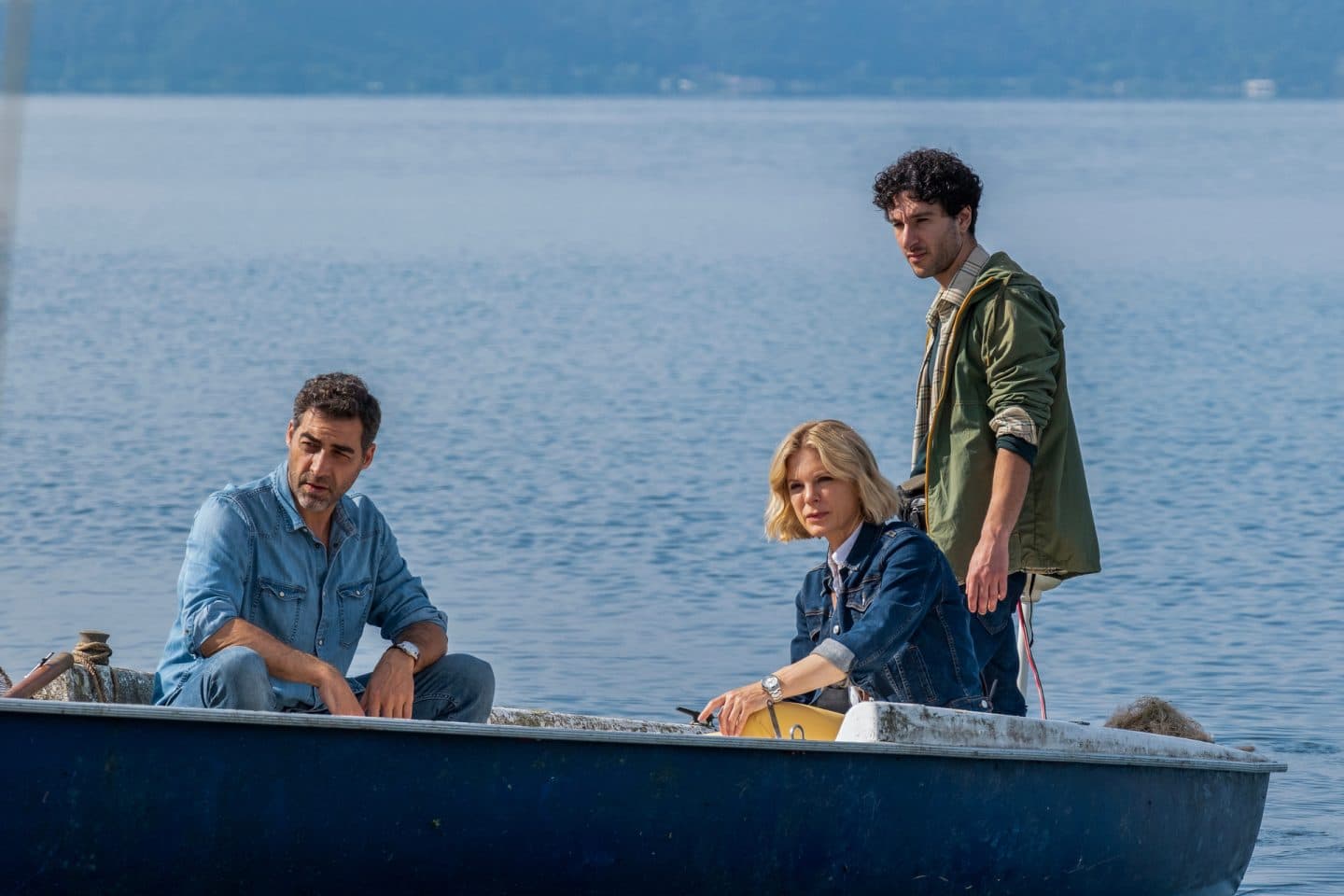 "Signora Volpe - Verstrickung": Giovanni (Giovanni Cirfiera) und Sylvia (Emilia Fox) sitzen in einem Boot auf dem See. Piero (Gianvincenzo Pugliese) steht am Heck.
