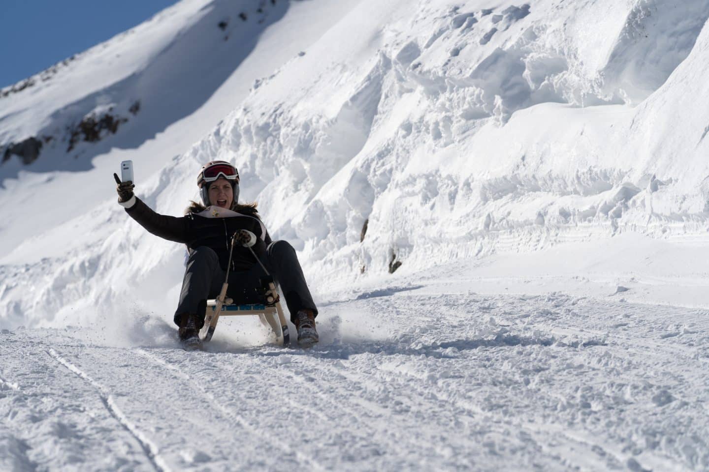 "Die Bergretter: Leuchtfeuer (1)": Nadine Kern (Lena Dörrie) rodelt mit einem Handy in der Hand den Berg hinab.
