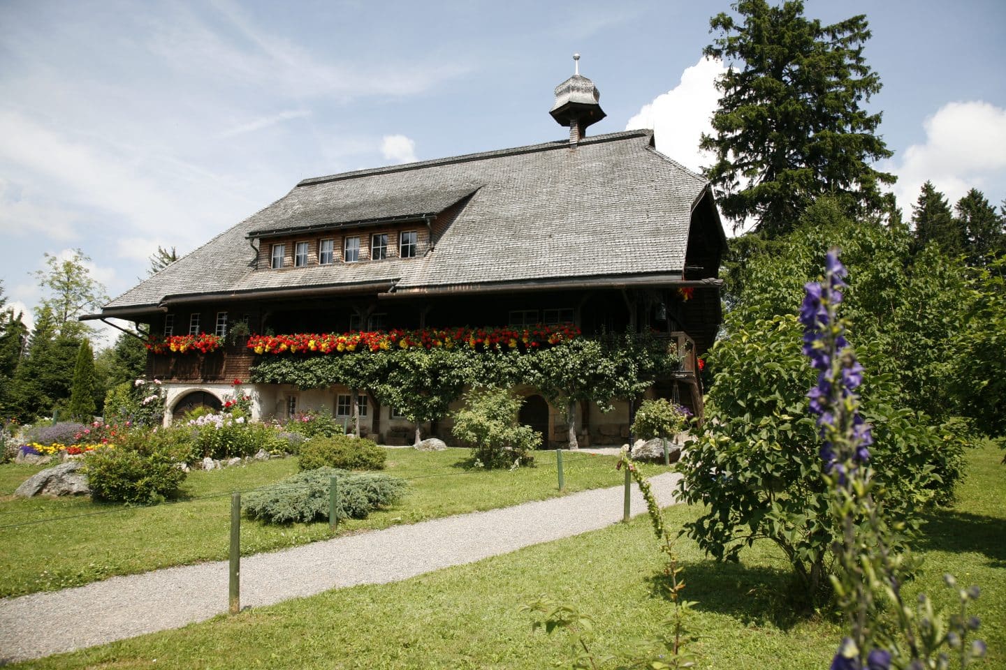 Historisches Schwarzwaldhaus „Hüsli“ in Grafenhausen, bekannt als Wohnhaus von Professor Brinkmann aus der TV-Serie „Die Schwarzwaldklinik“, mit blühenden Blumenkästen und gepflegtem Garten.