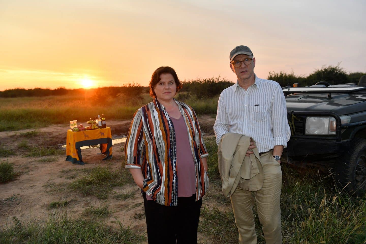 "Das Traumschiff: Afrika: Madikwe": In der Savanne: Paul Wagner (Cooper Dillon), Lisa Sommer (Klara Kleinheins), Katja Sommer (Isabell Horn) und Björn Wagner (Daniel Krauss) stehen nebeneinander vor einem Jeep und genießen die Landschaft. Sie wirken glücklich. Im Jeep sitzt eine Rangerin (Komparsin) und beobachtet die Vier.