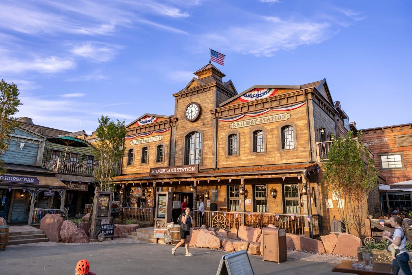 Westernstadt Silver Lake City im Europa-Park mit Holzgebäuden im Stil des Wilden Westens, darunter die Silver Lake Station, bei Tageslicht mit Besuchern im Vordergrund.